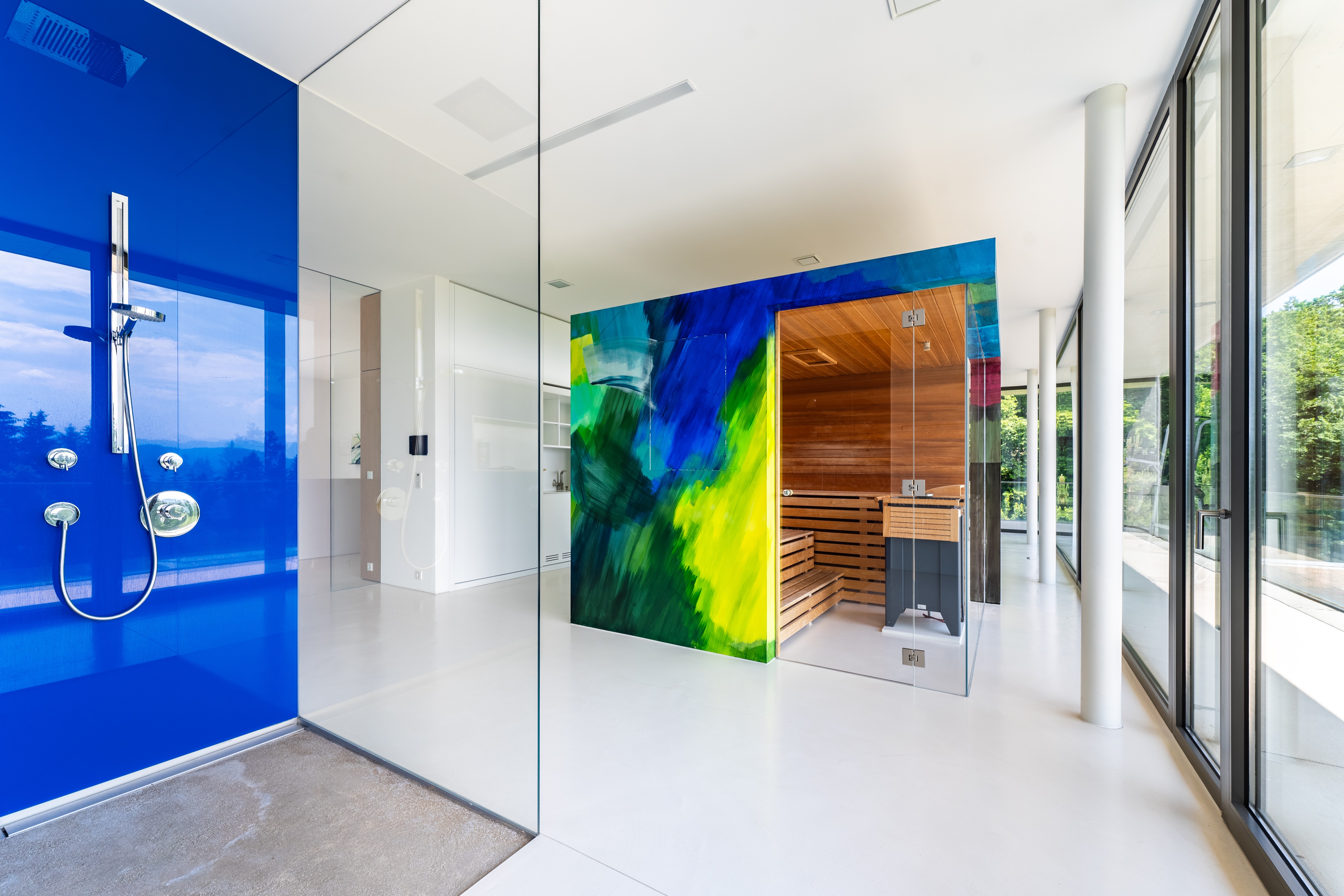 Wellnessbereich mit blauer Akzentwand, Glaszone und Designsauna