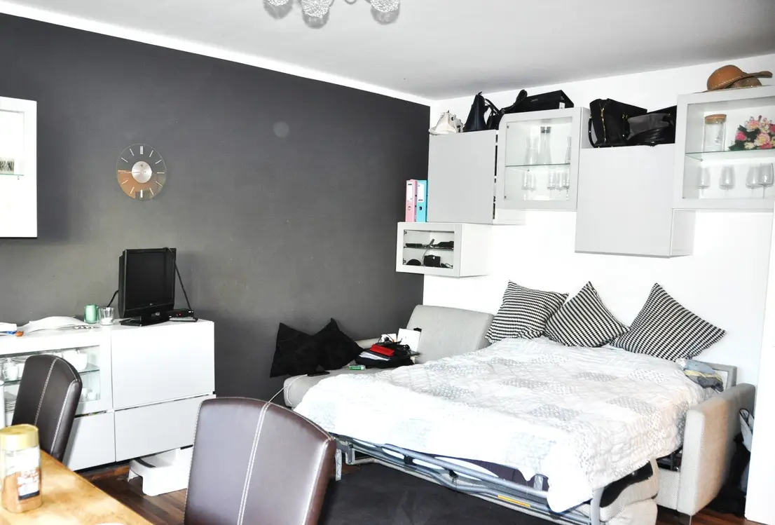 Wohnraum mit Schlafsofa, TV-Bereich und Hängeschränken