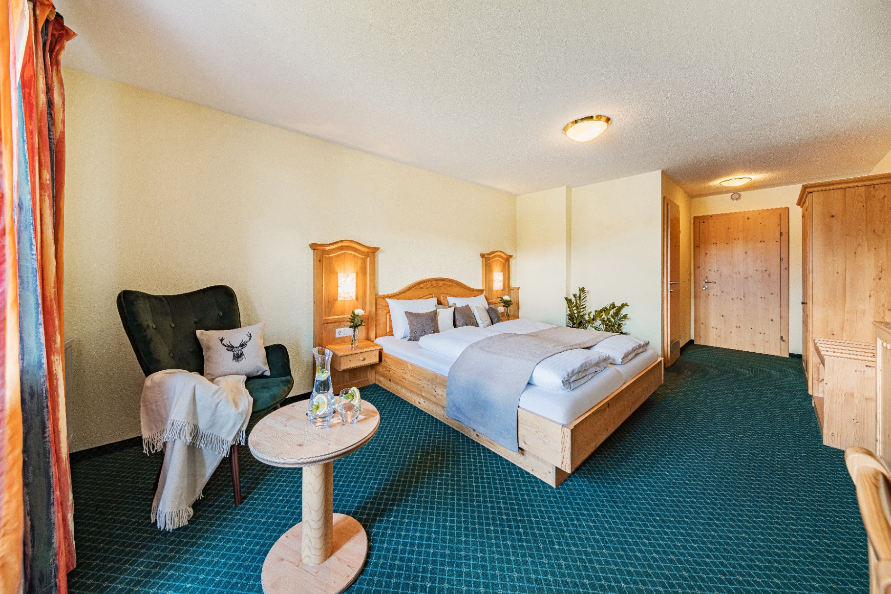 Klassisches Hotelzimmer mit Zirbenholz-Mobiliar und Ohrensessel